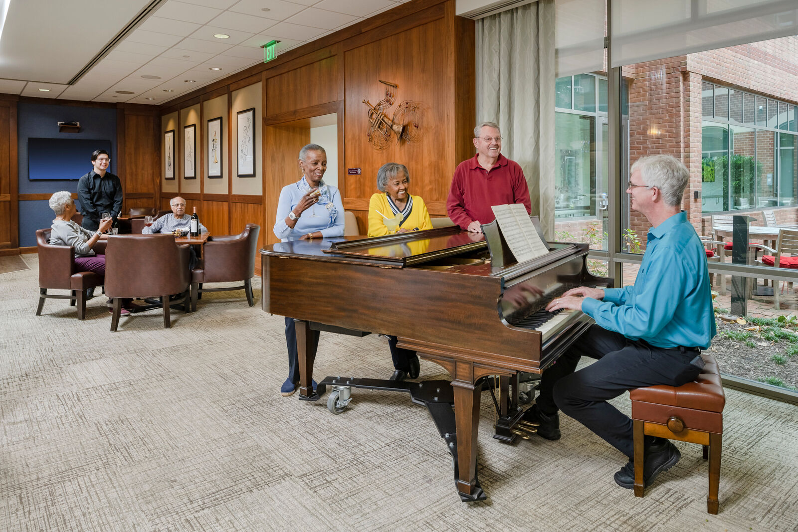 man playing at the piano and residents enjoying cocktails listening
