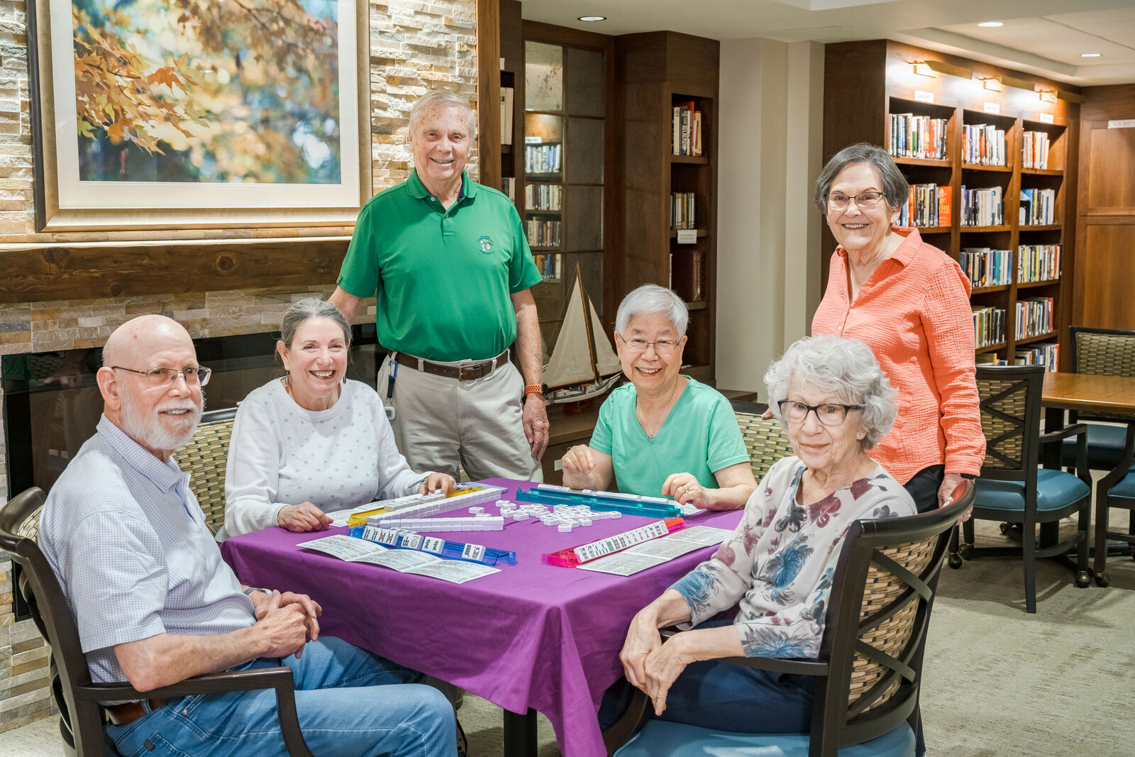A group of seniors in the library playing and watching Mahjong