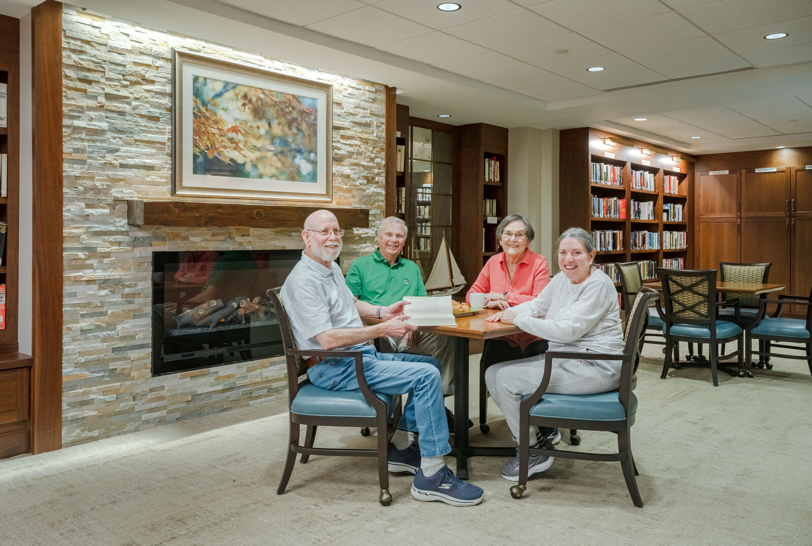 two couples sitting at a table in the library having book club