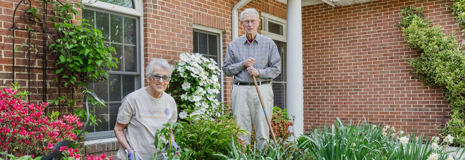 couple working in garden in front of brick Villa by entrance