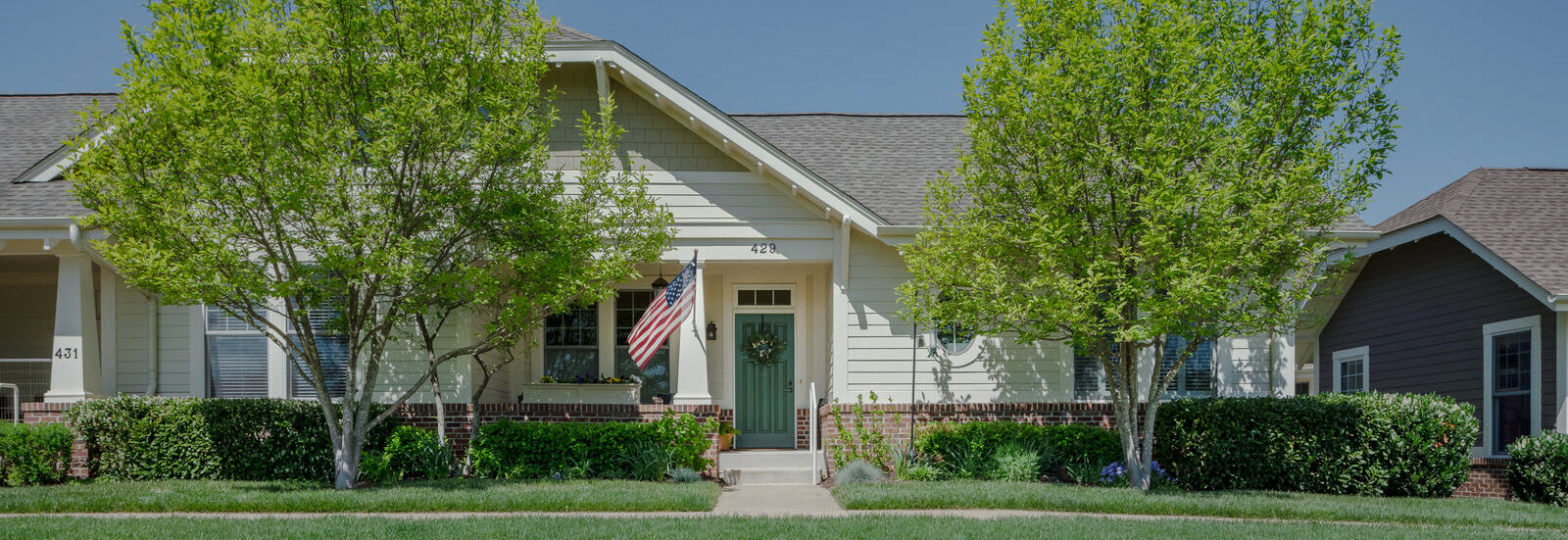front porch of Craftsman style Courtyard home with green lawn and American flag