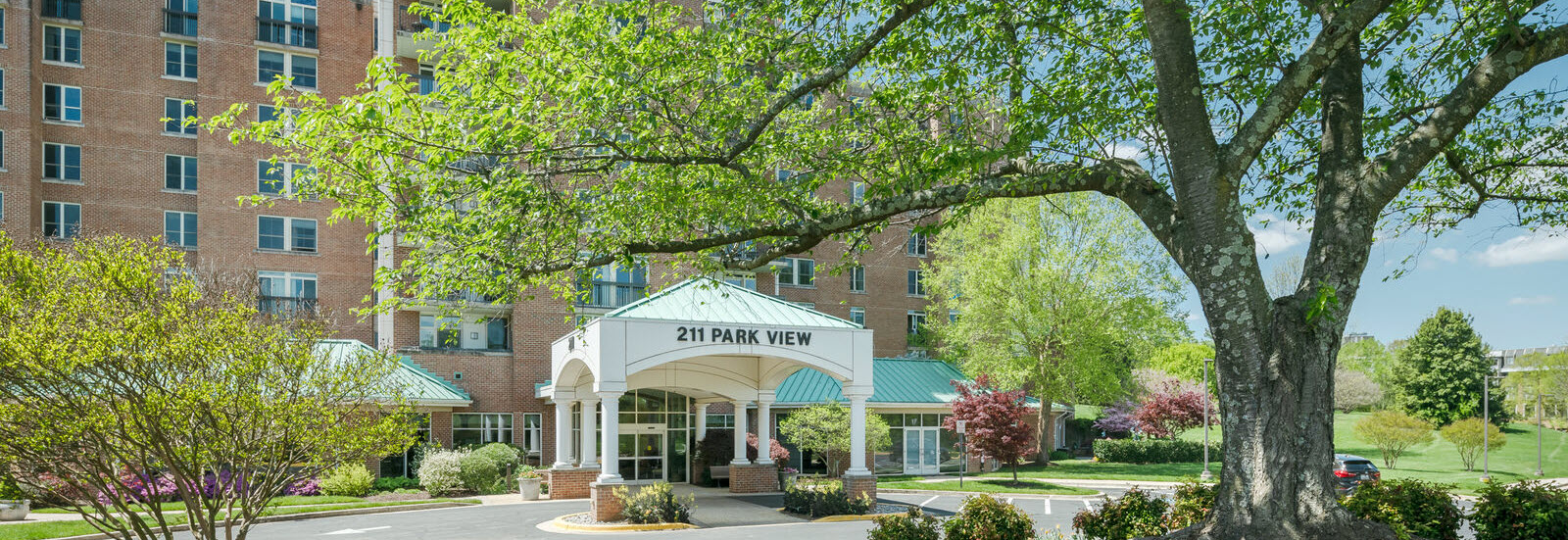 covered entrance to Park View apartments with green lawn and trees in foreground